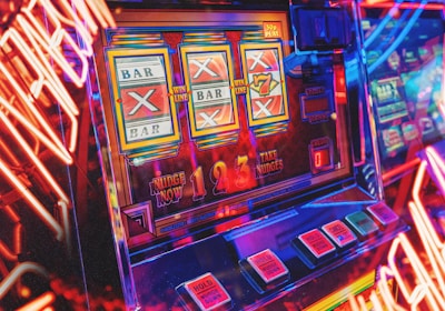 A vibrant scene featuring a classic slot machine with bright neon lights surrounding it. The slot machine displays symbols like 'Bar' and '7' and is set in a lively arcade environment. Reflections and colorful lighting add a sense of excitement and motion.
