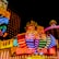 Bright neon lights and colorful signage adorn the exterior of Casino Lisboa, creating a vibrant and lively atmosphere. The façade features bold, multicolored designs with a mix of English and Chinese characters prominently displayed. The lights form intricate patterns and shapes, contributing to the energetic ambiance of the scene.