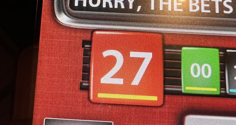 A digital display screen showing a casino betting interface, with text prompting to hurry bets and a highlighted number 27 in red. There are options for betting amounts and a 'share bets' button.